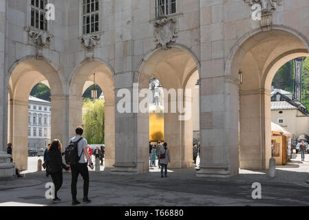 Altstadt, Salzbourg voir de deux jeunes gens à l'approche d'un grand colonnade séparant la Domplatz de la vieille ville de Salzbourg en Kapitelplatz, Autriche. Banque D'Images