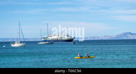 Un couple une pagaie kayak jaune avec voiliers et la National Geographic Venture bateau de croisière dans l'arrière-plan de la côte de l'Ile San Francisco, Baja Banque D'Images