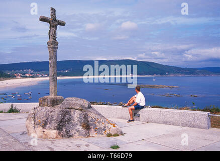 L'homme assis à la vue sur la plage de Langosteira. Finisterre, province de La Corogne, Galice, Espagne. Banque D'Images