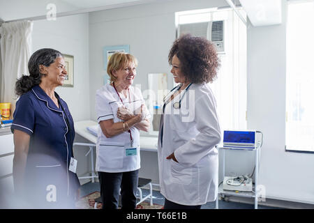 Femme médecin et infirmières parler en salle d'examen clinique Banque D'Images