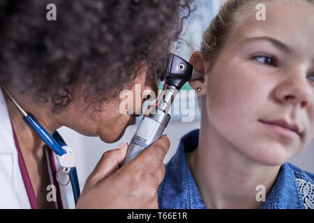 Close up femme pédiatre à l'aide d'un otoscope, l'examen de l'oreille du patient de fille Banque D'Images