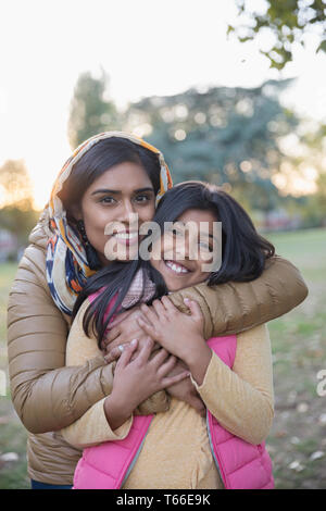 Portrait heureux mère musulmane en hijab hugging daughter in park Banque D'Images