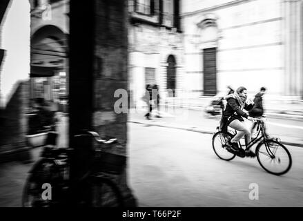 Pise, Italie, 12/02/2019 : dans le centre de la ville de Pise en Toscane une fille va vite en vélo. Photo prise lors d'une vacation. Banque D'Images