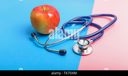 Stéthoscope et apple entre le bleu et le rouge, le concept de la frontière de la santé et de la maladie, en bonne santé et mode de vie malsain. Banque D'Images