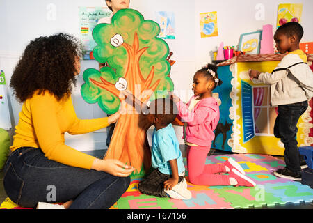 Groupe d'origine africaine noire à la recherche les enfants à apprendre les lettres de l'alphabet en mettant sur l'arbre dans la classe de maternelle Banque D'Images
