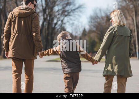 Les jeunes professionnels famille Père Mère et fils. Vue de derrière le parc de la ville par la marche. Banque D'Images