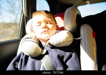 Petit enfant dormant dans location de fauteuil à l'arrière en road trip. Banque D'Images