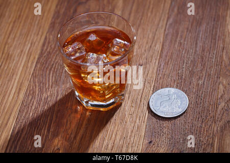 Verre de whisky et de la glace avec de vieux silver dollar sur table bar en bois Banque D'Images