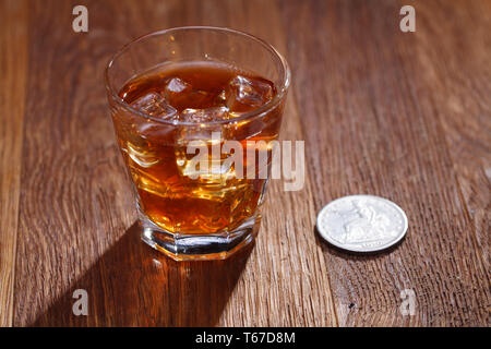 Verre de whisky et de la glace avec de vieux silver dollar sur table bar en bois Banque D'Images