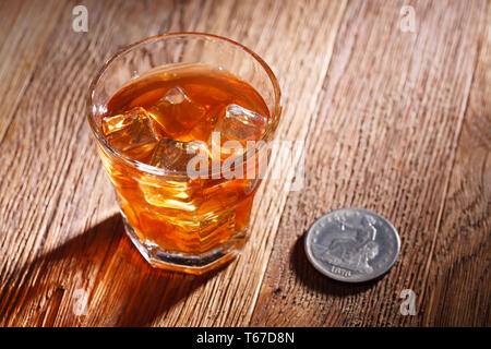 Verre de whisky et de la glace avec de vieux silver dollar sur table bar en bois Banque D'Images