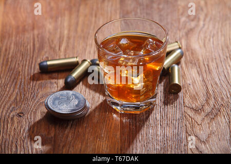 Verre de whisky et de glace avec munitions old silver dollar sur table bar en bois Banque D'Images