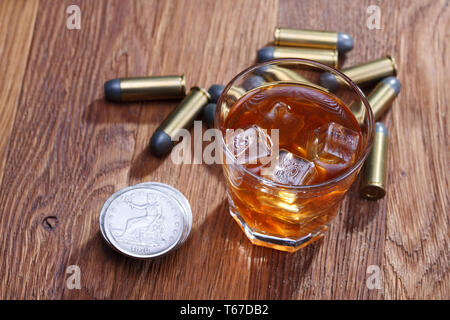 Verre de whisky et de glace avec munitions old silver dollar sur table bar en bois Banque D'Images