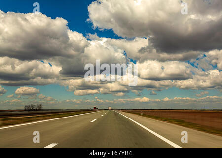 Location de voiture rapide. Motion de la vitesse sur la route fond d'image dans la campagne avec de beaux nuages Banque D'Images