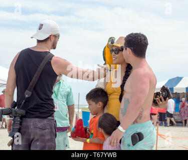 Un photographe met un ara bleu et or sur l'épaule d'une femme avant de prendre une photo au Texas 2019 Sandfest à Port Aransas, Texas USA. Banque D'Images