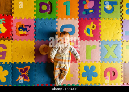 Adorable smiling baby vu de dessus en pyjama, couché sur le dos dans son jouet prix. Banque D'Images