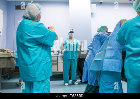 Chirurgie, Médecine et personnes concept - groupe des chirurgiens en salle d'opération à parler de l'hôpital et la préparation à l'opération Banque D'Images