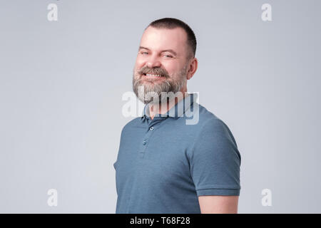 Confiant senior man with beard en bleu t-shirt smiling Banque D'Images