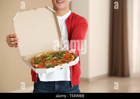 Young man holding box avec pizza savoureuse à l'intérieur Banque D'Images