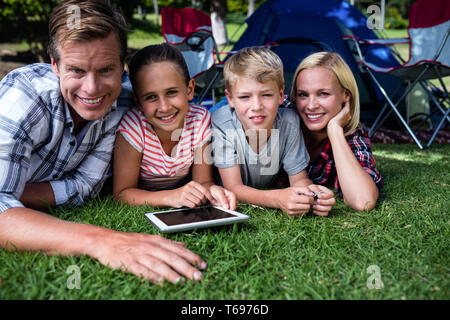 Portrait of a family lying on grass and using digital tablet Banque D'Images