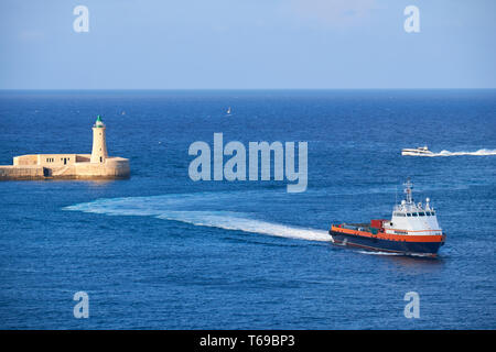 Un moteur de bateau entre dans le Grand Port près du phare de Saint Elmo, La Valette. Banque D'Images