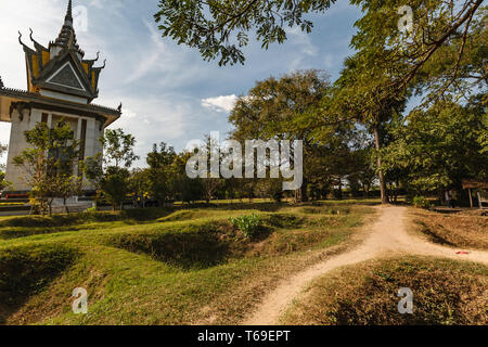 Une vue des champs de la mort au Cambodge, où le mémorial de Choeung Ek se dresse comme un sombre rappel des atrocités commises sous le régime des Khmers rouges. Le paysage, marqué par des fosses communes et une pagode sereine, sert de lieu de mémoire et de réflexion pour les visiteurs. Banque D'Images