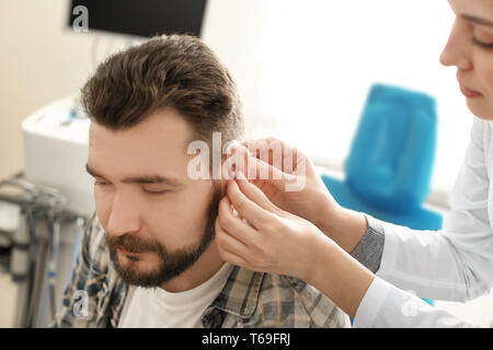 Oto-rhino-laryngologiste mettre dans l'aide auditive de l'oreille de l'homme à l'hôpital Banque D'Images