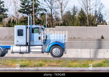 Profil de transport de marchandises de qualité industrielle gros camion camion semi bleu tracteur avec cabine de jour et petit compartiment derrière d'exécution sur le r Banque D'Images