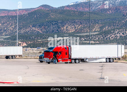 Chauffeur de camion cassé réparation de qualité industrielle américaine de transport de gros camion rouge semi truck tracteur à ouvrir le capot se dresse sur le chariot st Banque D'Images