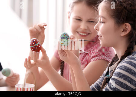 Cute little girls peinture oeufs pour Pâques à la maison Banque D'Images