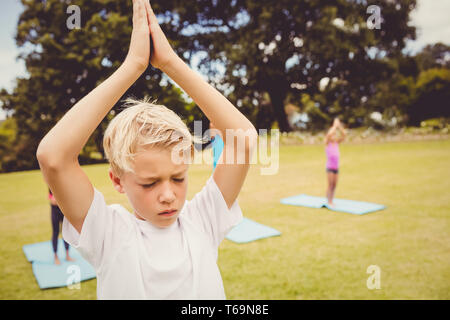 Gros plan sur un jeune garçon faisant du yoga avec d'autres enfants Banque D'Images