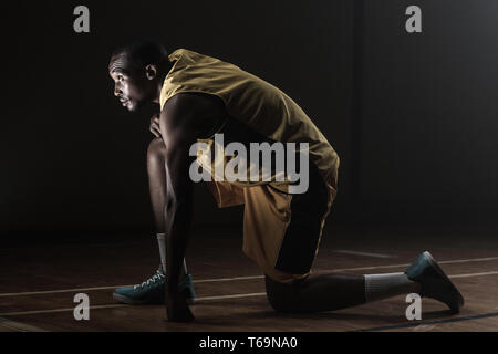 Basket-ball prépare à jouer avec genou sur le sol et jusqu'à la Banque D'Images
