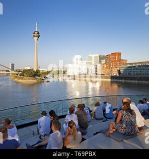 Les gens sur une terrasse de restaurant avec vue sur la tour du Rhin, Düsseldorf, Allemagne Banque D'Images