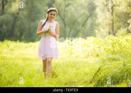 Jeune fille dans la lumière de l'été habiller la collecte des fleurs sauvages Banque D'Images