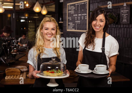 Jolies serveuses posant devant le comptoir café présentant et pie Banque D'Images