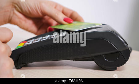 Femme avec carte est à l'aide du terminal de paiement, non en espèces, la borne émet un chèque des mains, close-up, vue de côté. Banque D'Images