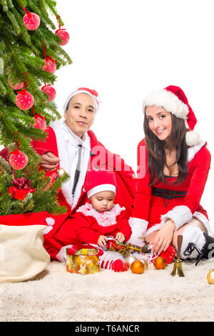 Famille heureuse dans la veille de Noël à la maison assis près de sapin décoré Banque D'Images