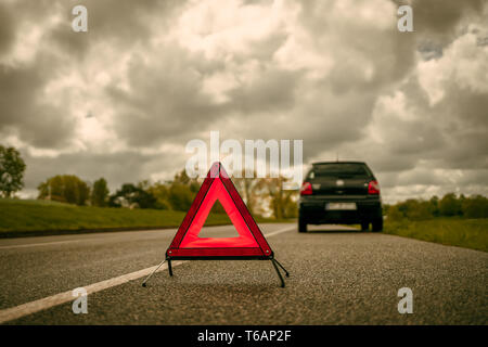 Un triangle d'avertissement à l'avant d'une voiture avec une ventilation sur une bande latérale d'une route de campagne Banque D'Images