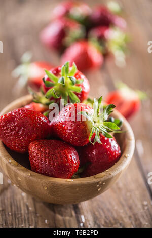 Laver les fraises juteuses dans bol en bois sur la table de cuisine Banque D'Images