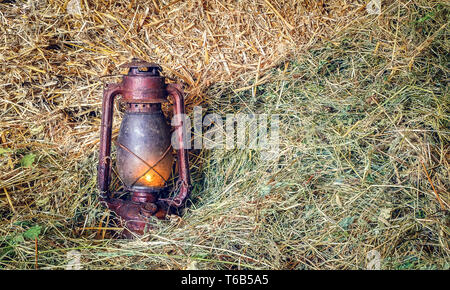 Vintage lampe lanterne à huile allumé sur la paille Banque D'Images