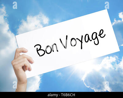 Bon voyage Bon Voyage (en français) sur du papier blanc. Tenir la main de l'homme papier avec texte. Isolé sur fond de ciel Banque D'Images