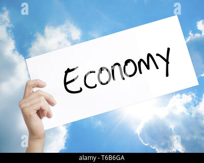 Signe de l'économie sur du papier blanc. Tenir la main de l'homme papier avec texte. Isolé sur fond de ciel. Banque D'Images