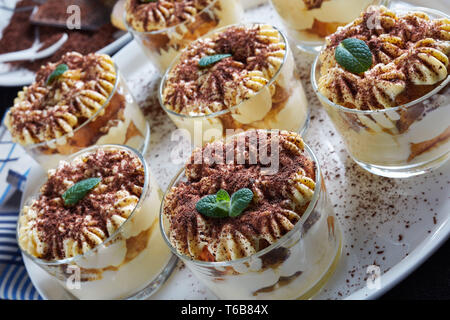 Close-up de tiramisu à lunettes rondes saupoudré de cacao en poudre sur une assiette, dessert italien de savoiardi biscuits, oeuf, sucre, café, mascarpone Banque D'Images