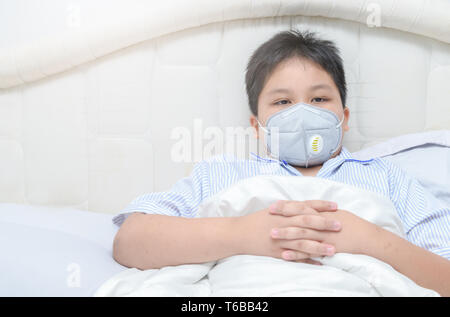 Fat boy obèses portant un masque anti-poussières PM2,5 sur lit, concept de soins de santé Banque D'Images