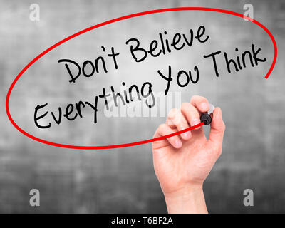 Man main écrit ne pas croire tout ce que vous pense avec marqueur noir sur l'écran visuel. Banque D'Images