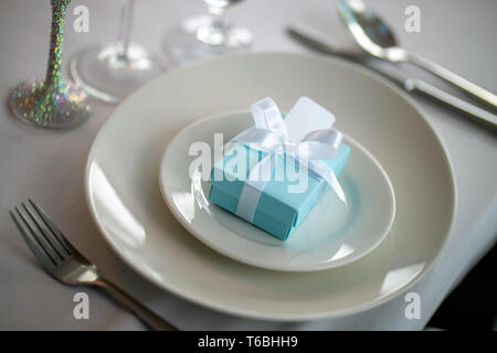 Table de fête avec boîte cadeau fait main sur la plaque. Boîte cadeau fait main bleu clair dans la plaque et la fourchette sur la table de mariage. Banque D'Images