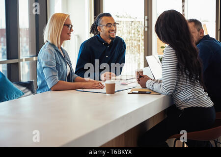 Groupe de divers collègues discuter d'affaires ensemble tout en ayant une rencontre autour d'une table dans un bureau Banque D'Images