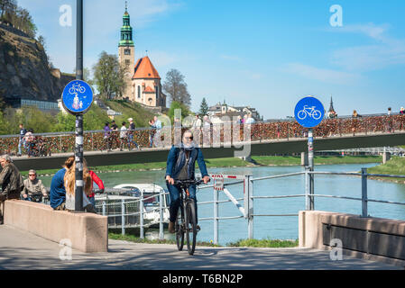 Vélo femme, vue d'une jeune femme à vélo sur une piste cyclable dans la ville de Salzbourg avec le pont Makartsteg en arrière-plan, en Autriche. Banque D'Images