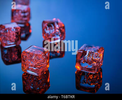 Cubes de glace scintillante sur bleu reflective surface Banque D'Images