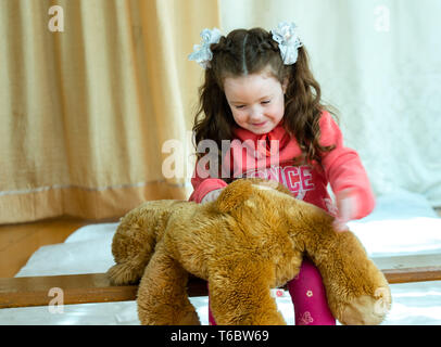 Petite fille en colère battant son ours en peluche - concept de violence domestique. Fille 4-5 ans punit ours en peluche. Banque D'Images