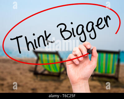 Man main écrit voir plus grand avec marqueur noir sur l'écran visuel. Banque D'Images